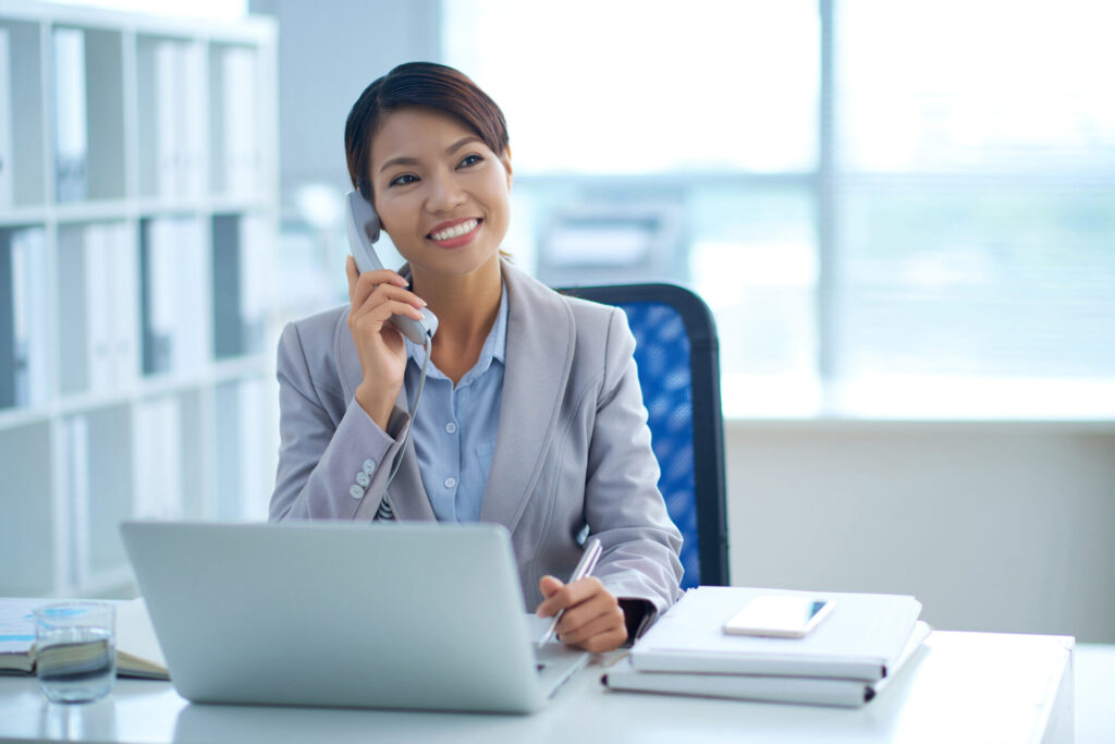 Portrait of smiling young female business executive talking on the phone in her office