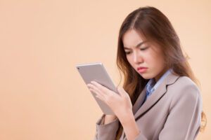 portrait of upset, angry, frustrated asian business woman using computer tablet
